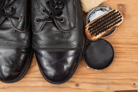 Shoe polish with brush, cloth and worn boots on wooden platform.の写真素材
