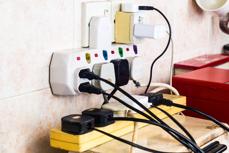 Multiple electricity plugs on adapter risk overloading and dangerous.の写真素材