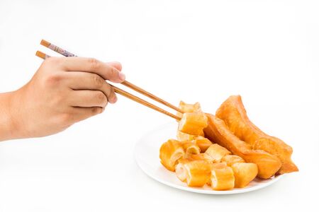 Chopsticks reaching for a piece of You Tiao, or fried bread stickの写真素材