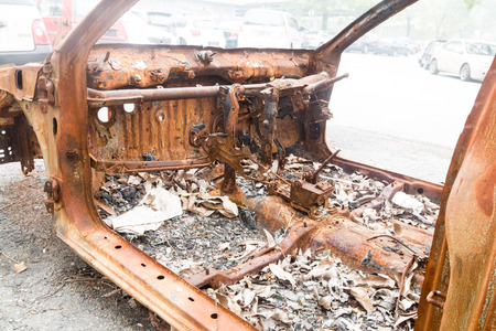 Rusty chassis of a burnt car abandoned by the side of the streetの写真素材