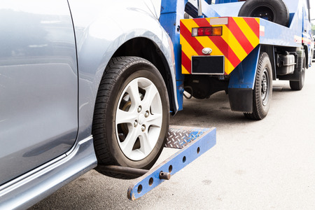 Tow truck towing a broken down car on the street.の写真素材