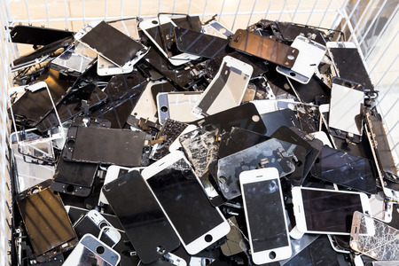 Stack and piles of damaged smart phone body and cracked LCD screen in bin.