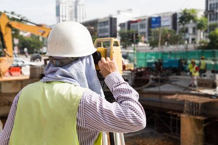 Engineer operating the dumpy automatic level instrument at construction siteの写真素材