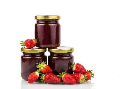 Organic strawberry jam in transparent glass jar on white background with fresh strawberries surroundingの写真素材
