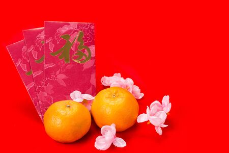 Mandarin oranges with red packets bearing Good Luck character in Chinese on red backgroundの写真素材