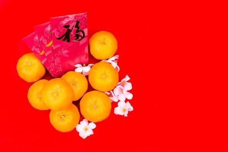 Mandarin oranges with red packets bearing Good Luck character in Chinese on red backgroundの写真素材
