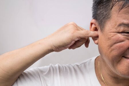 Man un-hygienically cleaning ear using finger with ticklish expressionの写真素材