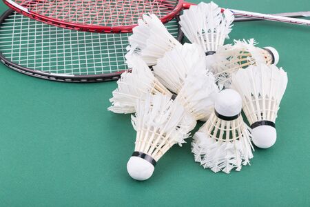 Group of used and worned out badminton shuttlecock and rackets on green mat PVC courtの写真素材