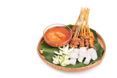 Freshly barbecue chicken and beef satay with gravy, rice, cucumber and onion served on traditional rattan weaved plate with banana leafの写真素材