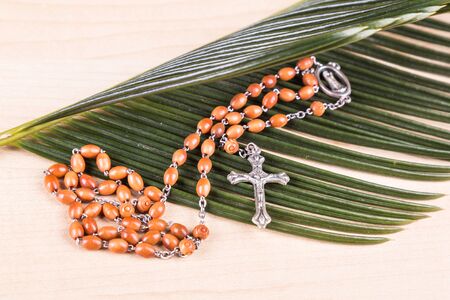 Closeup of Holy Catholic rosary with crucifix and beads on palm leafの写真素材