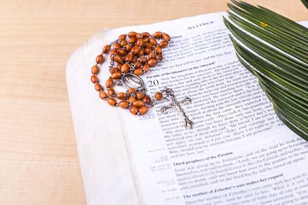 Closeup of Holy Catholic rosary with crucifix and beads on palm leafの写真素材