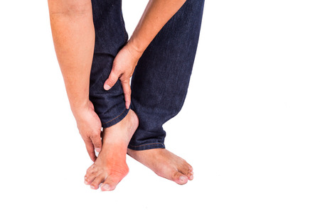 Man in jeans embraces foot with painful and swollen gout inflammationの写真素材