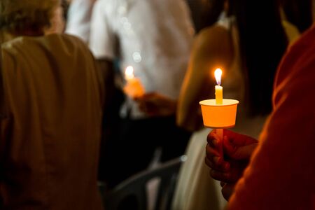 Closeup of people holding candle vigil in darkness expressing and seeking hopeの写真素材