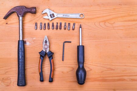 Essential basic tools set consisting hammer, plier, screwdriver and adjustable crescent on wooden backgroundの写真素材