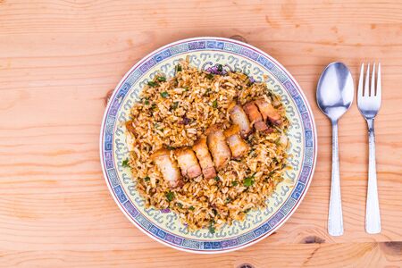Delicious Chinese spicy fried rice with roast pork in plate served on wooden tableの写真素材