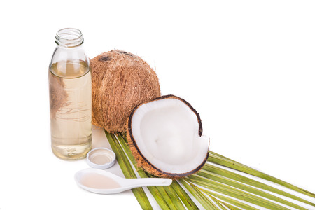 Cold pressed extra virgin coconut oil in bottles with coconut fruits in white backgroundの写真素材