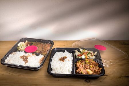 Two convenient take-away meal boxes with rice, meat and vegetable on wooden table topの写真素材