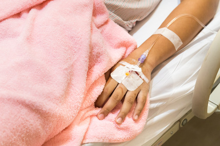 Patient hand in hospital with saline solution intravenous iv
