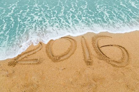 2016 inscription on sandy beach washed off erase with approaching wave