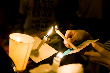 Group of people lighting candle vigil in darkness seeking hope, worship, prayerの写真素材