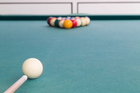 Focus on cue aiming white ball to break snooker billards on green table