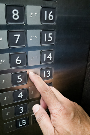 Closeup on user with vision disability reading Brialle on elevator panel with fingerの写真素材
