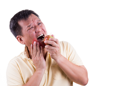 Conceptual of man with intense toothache pain after biting apple with thornsの写真素材