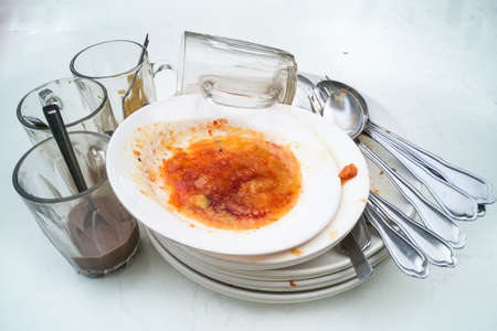 Pile of dirty oily messy plates, glass, cups, fork spoons after mealの写真素材