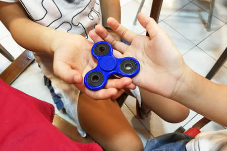 Underaged kids playing the fidget spinner. Maybe hazardous to kids and small children.の写真素材