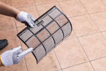 Person hand with glove pointing on thick dirty dust on air conditioner filter