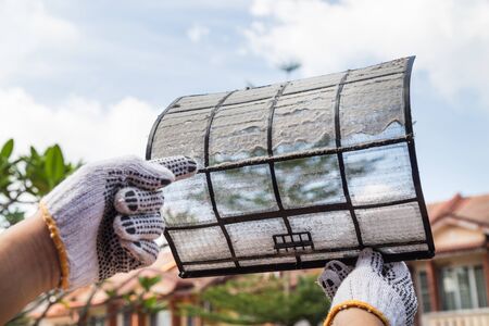 Person hand with glove pointing on thick dirty dust on air conditioner filter