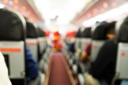 Defocused airplane cabin interior with seats, passengers and red flooringの写真素材