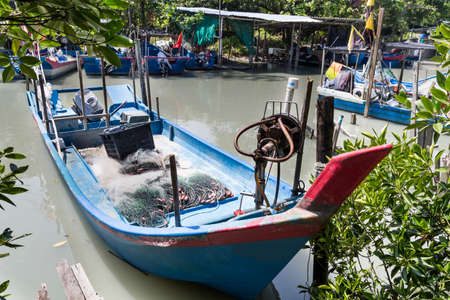 Traditional fisherman boat trawler berth on small jetty at river mouthの写真素材