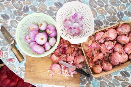 Onion skin being prepared peeled with knife, chopping board colander for cookingの写真素材