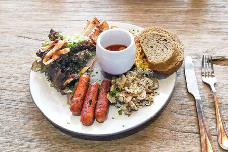 Big breakfast of sausage, mushroom, baked beans, salad, eggs, bacon, ham, wholemeal bread served on...
