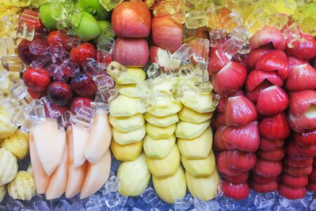 Fresh and refreshing sliced fruits variety neatly arranged and topped with iceの写真素材