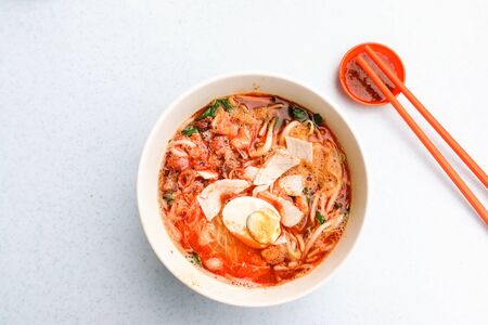 Overhead view of Penang popular prawn mee noodles with eggs, and small shrimp served on tableの写真素材