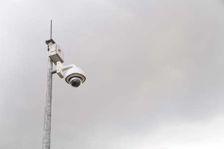 Outdoor security surveillance cctv camera against gloomy overcast sky with copy spaceの写真素材