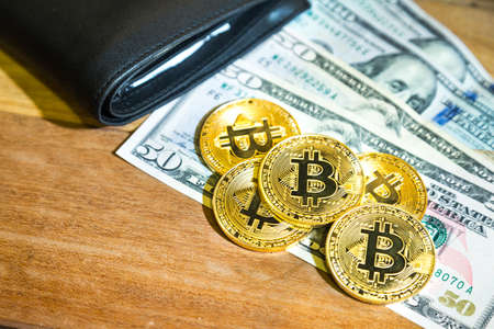 Conceptual cryptocurrency bitcoin with wallet on wooden table with US Dollar billの写真素材