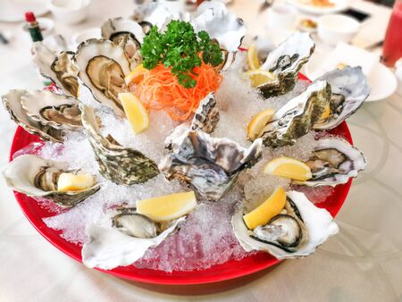 Fresh live raw oyster served with lemon and chili sauce in restaurant