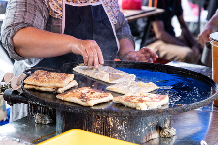 Seller preparing murtabak at street stall for iftar during muslim fasting month of Ramadan.の写真素材