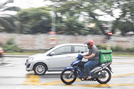 KUALA LUMPUR, MALAYSIA, September 17, 2019: Grabfood ordered online being delivered on motorbike by grab rider.  Grabfood is a fastest growing food delivery service in Asia.のeditorial素材
