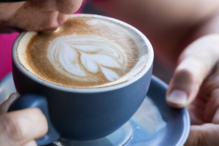 Closeup of Asian woman enjoying sipping coffee latte with artの写真素材
