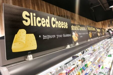 Cheese signage at supermarket refrigerated produce food section with defocused backgroundの写真素材
