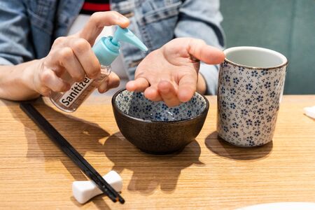 Person disinfecting hands with sanitizer before meal at dinner table
