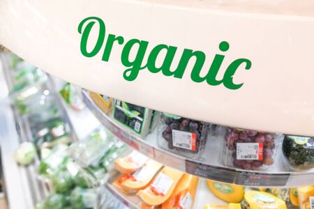 Organic word signage at supermarket vegetable and fruits refrigerated aisle sectionの写真素材