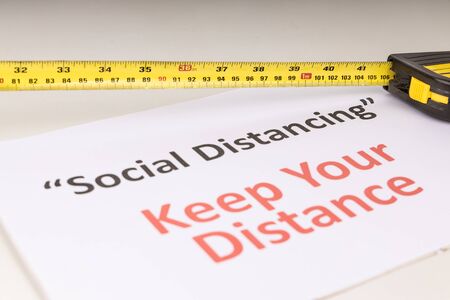 Social Distancing concept with measuring tape focused on 1 meter mark against Keep Your Distance placardの写真素材