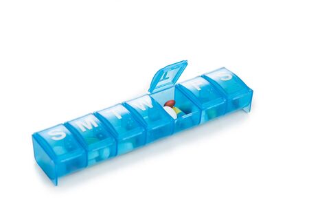 Pill organizer box storing doses of daily medicine on white backgroundの写真素材