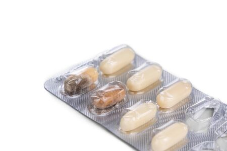 Strip of expired soft gel caplet medicine with mold on white background