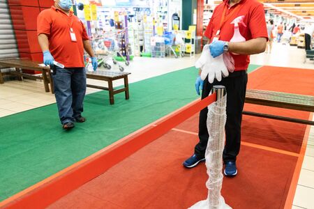 New normal lifestyle with inspectors requiring shoppers to sanitize hands and put on disposable gloves for protection before entering supermarket in Malaysiaの写真素材